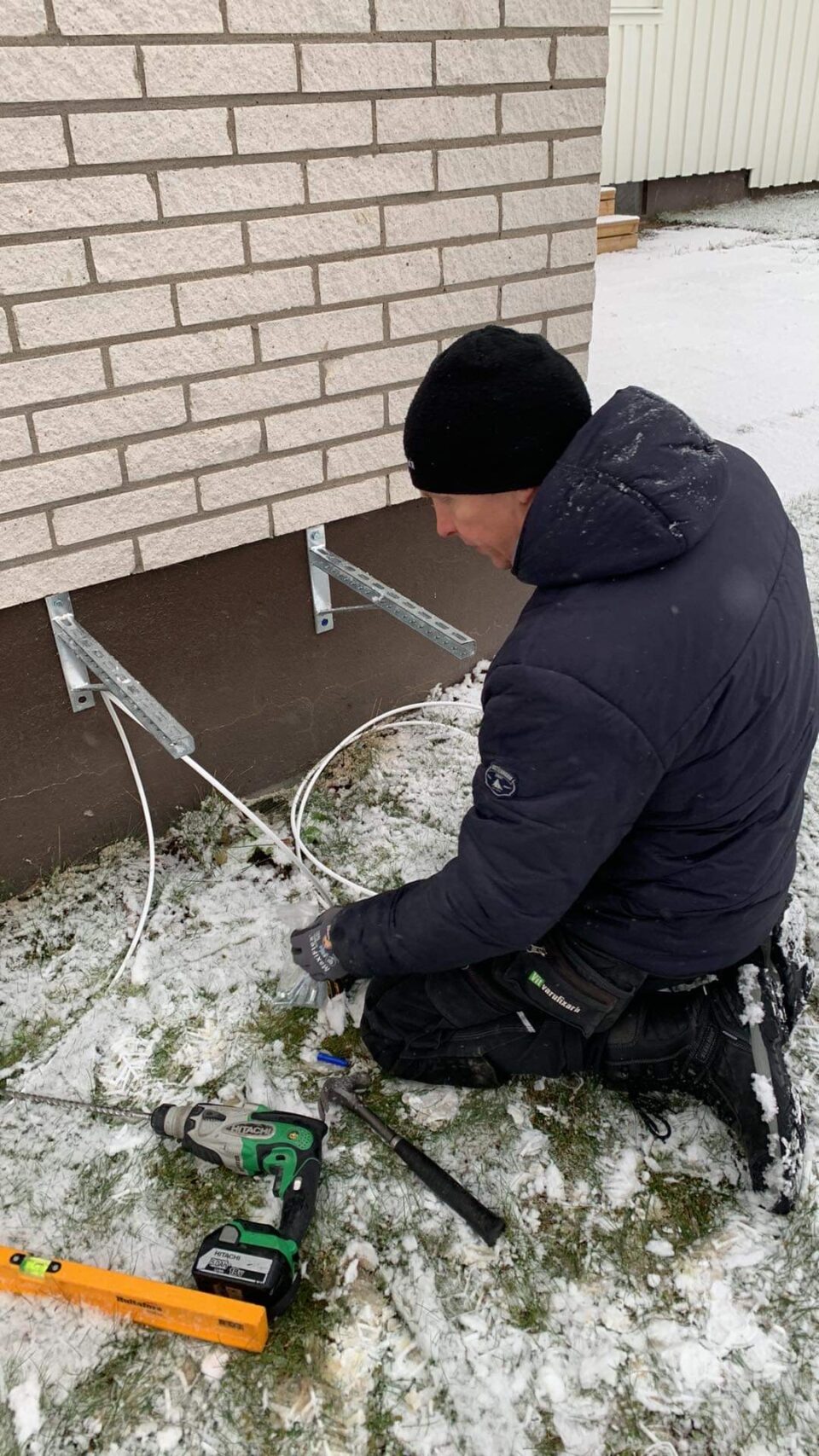 Robert monterar en luftvärmepump direkt på fasad. Givetvis med dämpande fjädrar som extra tillval för att minimera stomljud i huset.